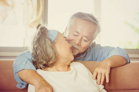 Close up portrait of happy senior asian couple hugging in living room, elderly couple at home conceptの写真素材