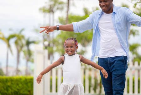Cheerful african american girl playing outdoor with her father in the parkの写真素材
