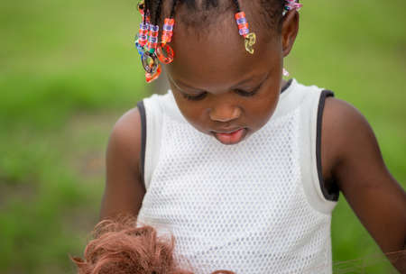 Close up of Little girl with doll at park with blurred green backgroundの写真素材