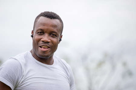 Cheerful african american man with wireless earpiece smiling at outdoor and looking at cameraの写真素材