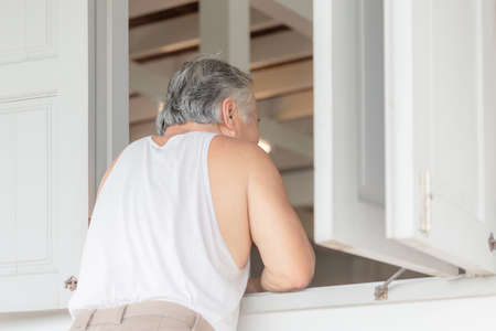 Senior asian man standing relax at the window