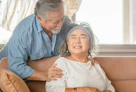 Close up portrait of happy senior asian couple hugging in living roomの写真素材