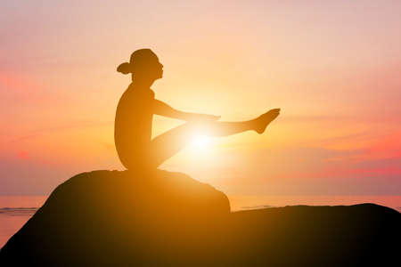 Silhouette of young woman with clipping path practicing yoga relaxing exercise at sunsetの写真素材