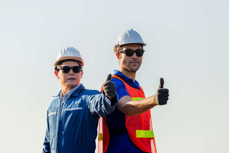 Cheerful factory worker and engineer man smiling with giving thumbs up as sign of Successの写真素材