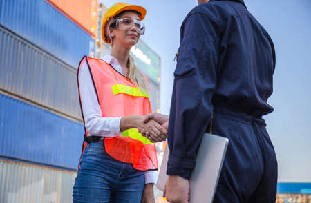 Engineer and worker handshake with blurred containers cargo background, Success and Teamwork conceptの写真素材