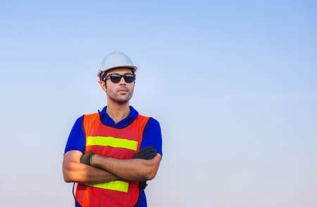 Cheerful factory worker man in hard hat smiling with arms crossed as sign of Successの写真素材