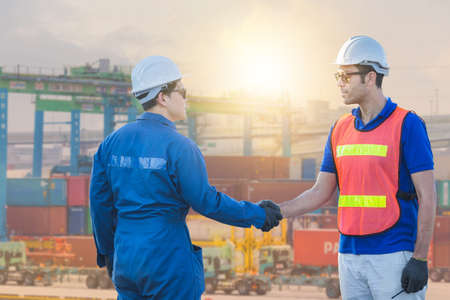 Engineer and worker handshake with blurred containers cargo background, Success and Teamwork concept with clipping pathの写真素材