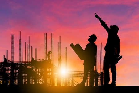 Silhouette of Engineer and worker with clipping path on building site, construction site at sunset in evening time.の写真素材