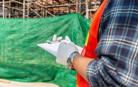 Close up of worker man holding clipboard checklist at construction siteの写真素材