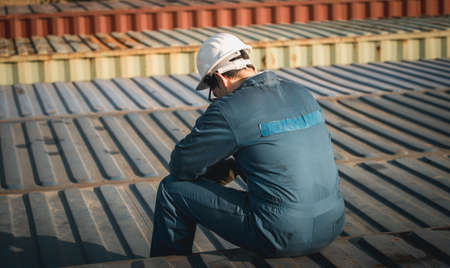 Lonely Foreman worker lost in depression on the containers box in the cargo, feeling sadness conceptの写真素材