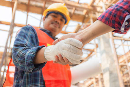 Close up of engineer and worker handshake with blurred construction site, Success and Teamwork conceptの写真素材