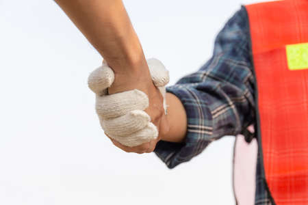 Close up of engineer and worker handshake with blurred construction site, Success and Teamwork conceptの写真素材