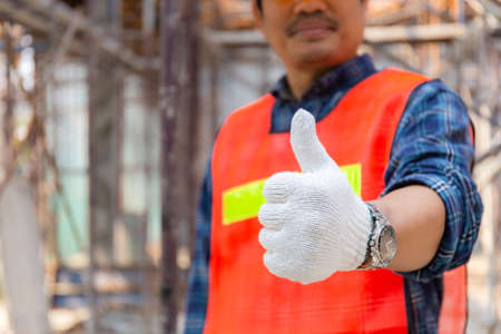 Engineer / worker man hand giving thumb up over blurred construction site, Successful conceptの写真素材