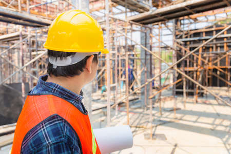 Engineer / foreman checking and planning project at construction site, Man holding blueprint with blurred backgroundの写真素材