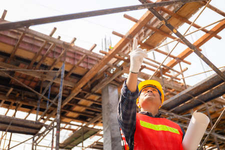 Engineer man checking and planning project at construction site, Man holding paper and point to forwardの写真素材
