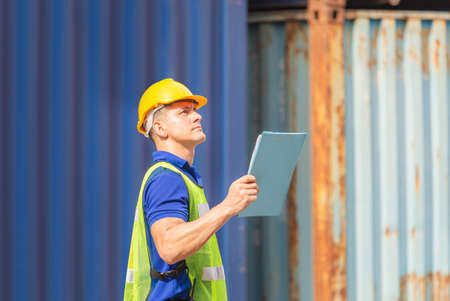 Worker man holding clipboard checklist and checking containers box from cargoの写真素材
