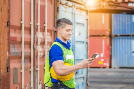 Engineer man uses mobile phone, Foreman worker using mobile smartphone in industry containers cargoの写真素材