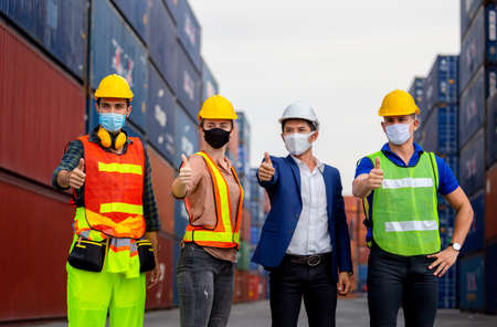 Success Teamwork Concept, Business people engineer and worker team wearing protection face mask against coronavirus with giving thumbs up as sign of successの写真素材