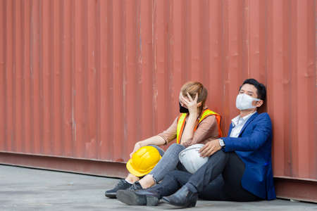 Young worker and engineer sitting failed and stressed at cargo containerの写真素材