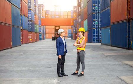 Engineer and foreman worker team in hardhat and safety vest control loading containers box from cargoの写真素材