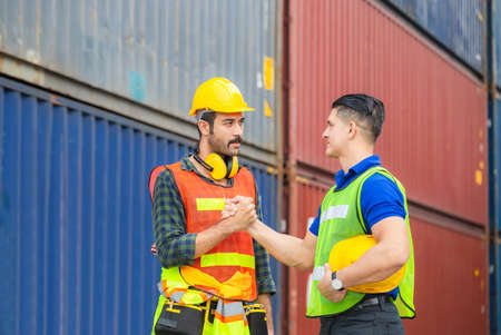 Engineer and worker soul brother handshake, thumb clasp handshake or homie handshake with blurred containers cargo background, Success and Teamwork conceptの写真素材