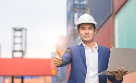 Cheerful engineer man holding laptop with giving thumbs up as sign of success
