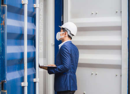 Engineer wearing protection face mask against coronavirus, Foreman worker checking containers box...