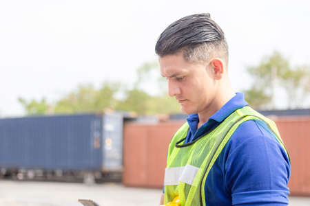 Engineer man uses mobile phone, Industrial worker using mobile smartphone in industry containers cargoの写真素材