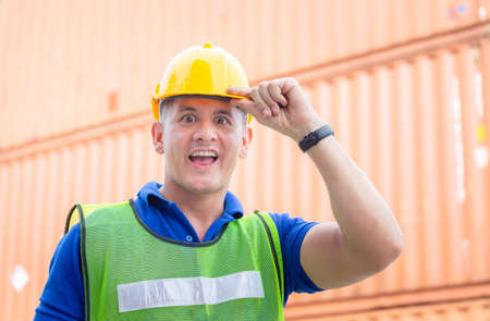 Funny factory worker man in hard hat smiling and looking at camera with joy, Happiness engineer at cargo containers conceptの写真素材