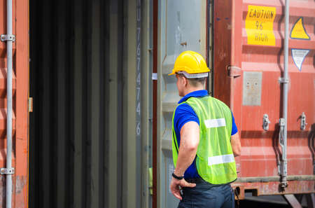 Engineer worker man in hardhat and safety vest checking containers box from cargoの写真素材