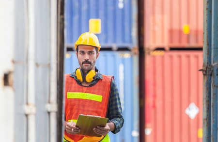 Worker man holding clipboard checklist and checking containers box from cargoの写真素材