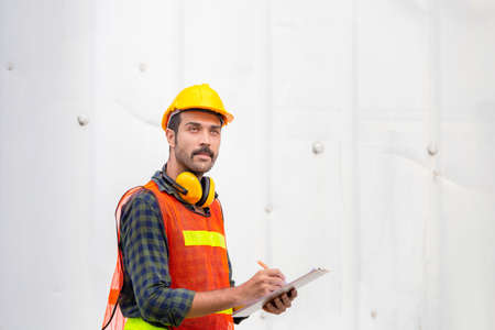 Factory worker man holding clipboard checklist checking containers box from cargoの写真素材