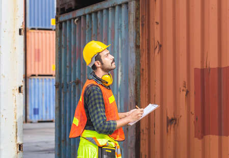 Worker man holding clipboard checklist and checking containers box from cargoの写真素材