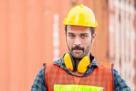 Portrait of Engineer man in hard hat and safety vest, worker with protective headphones at construction siteの写真素材