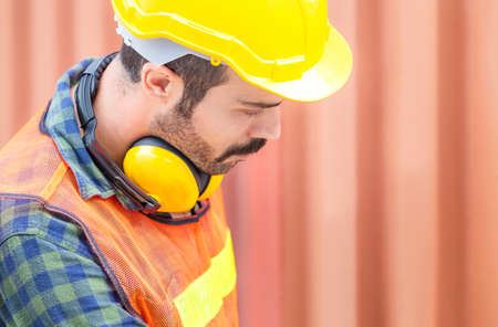 Close up of Worker man in hardhat and safety vest, Engineer checking containers box from cargoの写真素材