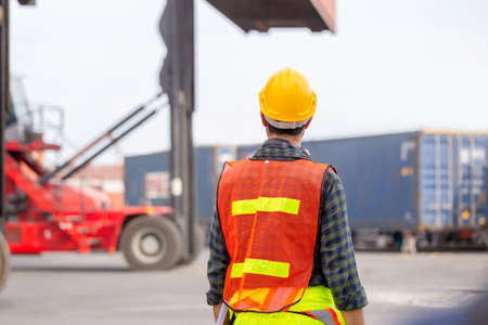 Engineer man in hardhat and safety vest control loading containers box from cargo, Logistic conceptの写真素材