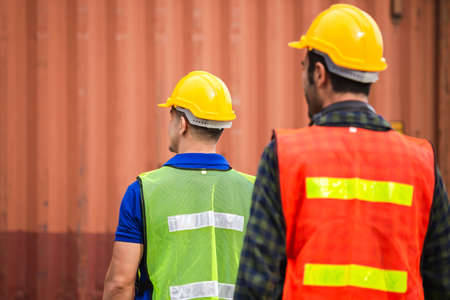 Rear view of Engineer and worker team in hard hat checking at containers cargoの写真素材