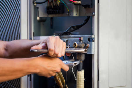 Technician man using a wrench fixing modern air conditioning system, Maintenance and repair conceptの写真素材
