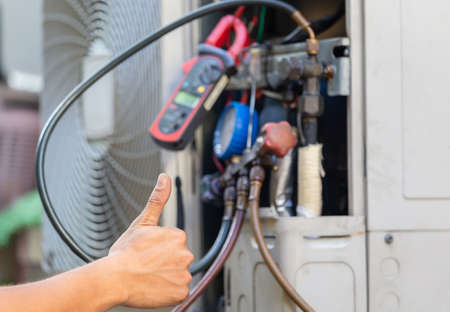 Close up of Air Conditioning repair man hand giving thumb up as sign of success, repairman fixing air conditioning systemの写真素材