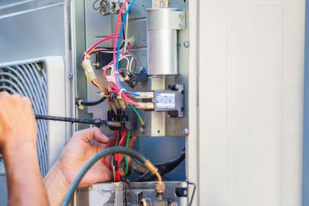 Male technician hands using a screwdriver fixing modern air conditioner, repairing and servicing, Maintenance and repairing conceptの写真素材