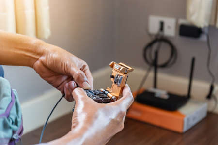 Selective focus of internet technicians man are cutting fiber optic cables with cutting tool and prepare for splicing, Home IT network conceptの写真素材