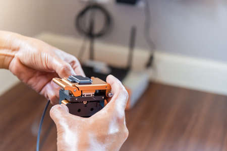 Selective focus of internet technicians man are cutting fiber optic cables with cutting tool and prepare for splicing, Home IT network conceptの写真素材
