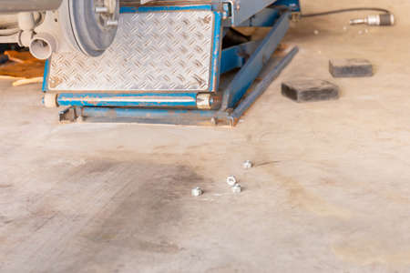 Garage floor with nut and car wheel clamp machine in process of new tire replacementの写真素材