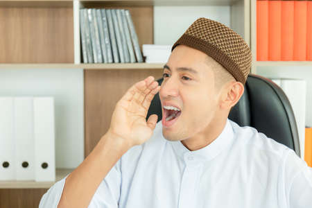 Happy young business arab middle eastern muslim man shouting and screaming loud to side with hand on mouth, Communication conceptsの写真素材