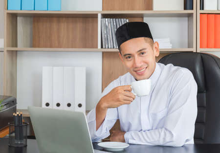 Happiness young business arab middle eastern man drinking coffee in office happy and smile faceの写真素材