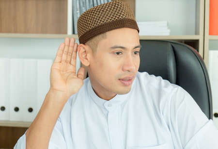 Happy young business arab middle eastern muslim man smiling with hand over ear listening an hearing to rumor or gossip, Communication conceptsの写真素材