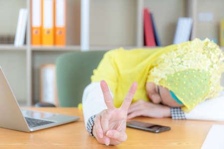 Arab middle eastern business woman sleeping at his desk, Women showing victory sign. Keep fighting concept.の写真素材
