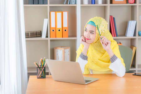 Dreaming Arab woman sitting relaxing in office, young muslim women smiling and joyfullyの写真素材