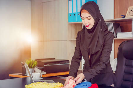 Selective focus of Young businesswoman arab middle eastern muslim looking and checking fabric in officeの写真素材