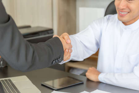 Arab middle eastern businessman and business woman make handshakes, finishing up meetingの写真素材